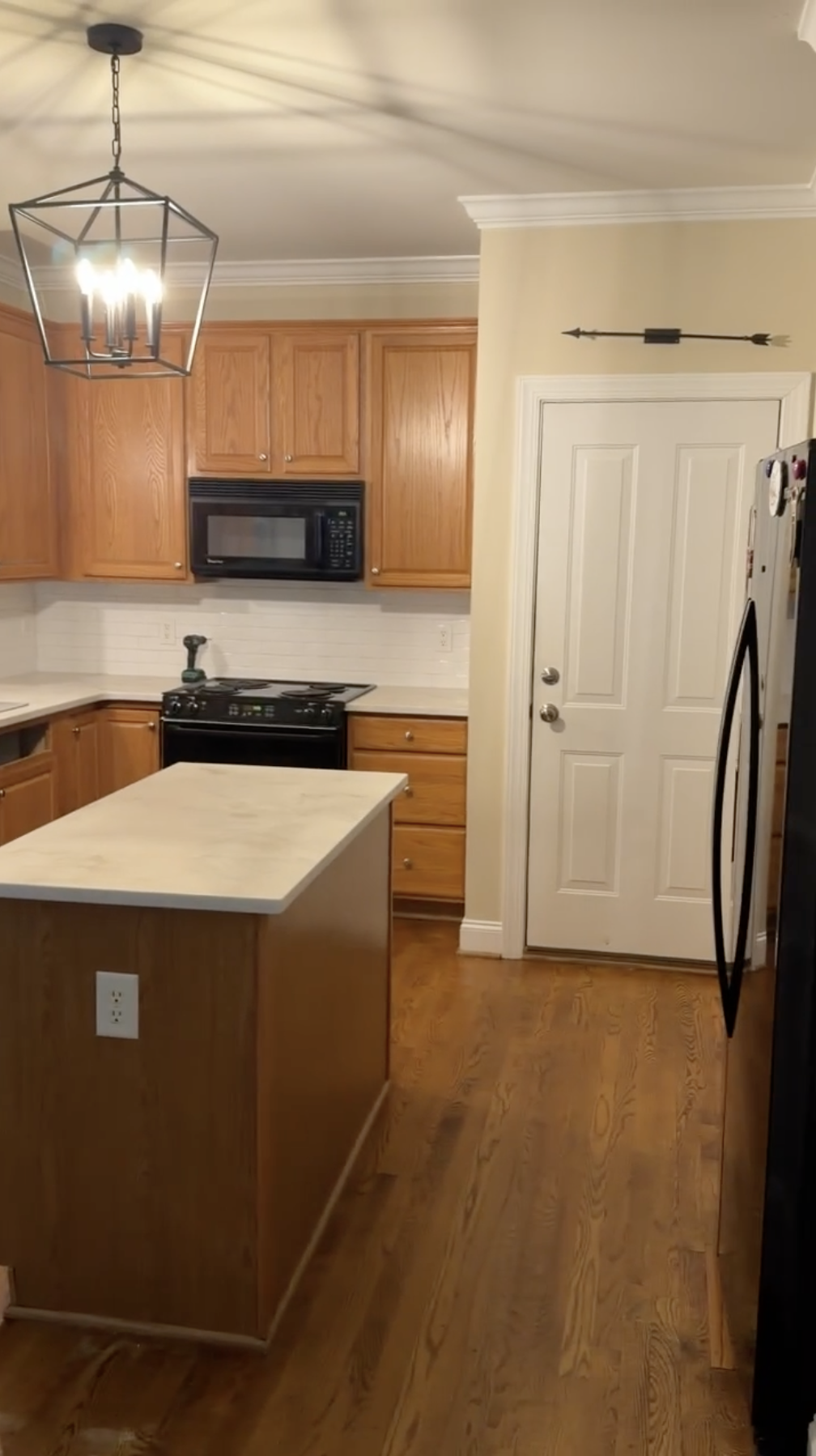 Waxhaw kitchen before — honey oak upper cabinets and island from entry angle