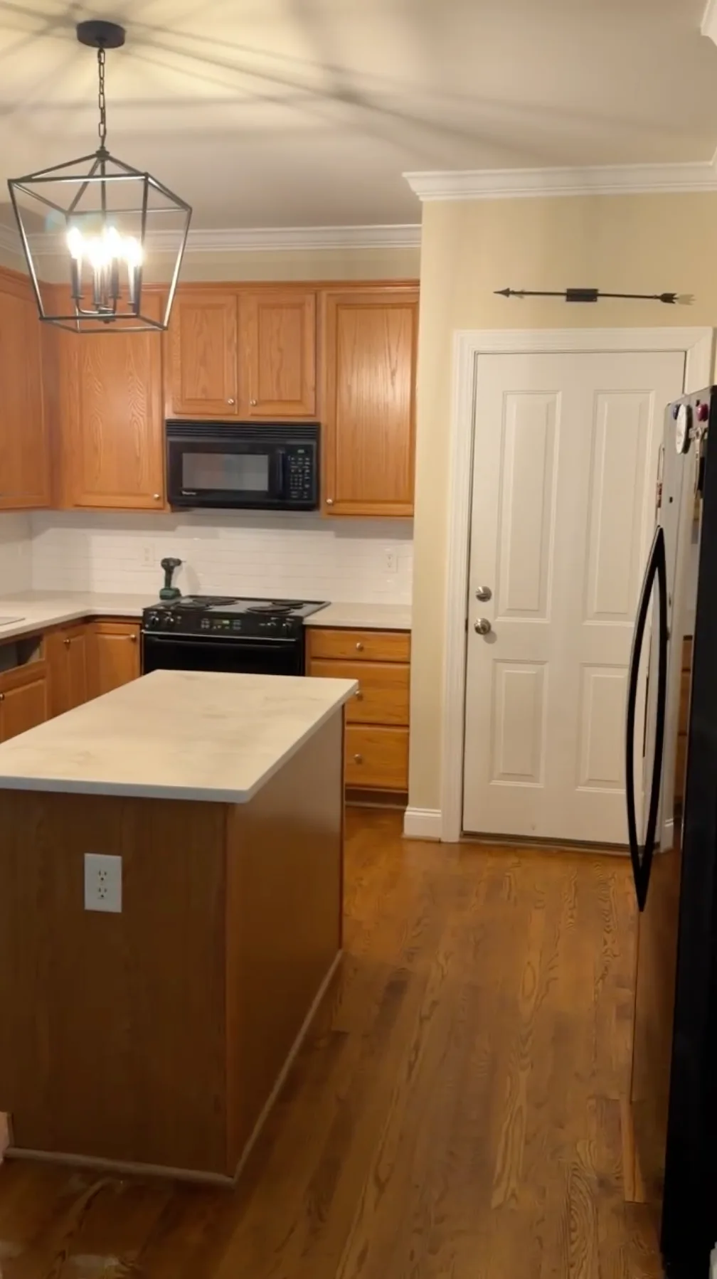 Waxhaw kitchen before — honey oak upper cabinets and island from entry angle